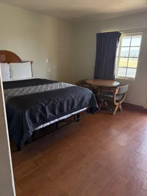 a bedroom with a bed and a table and a window at Apple Valley Motel in Apple Valley