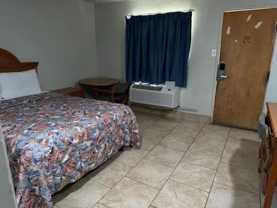 a bedroom with a bed and a table and a window at Apple Valley Motel in Apple Valley