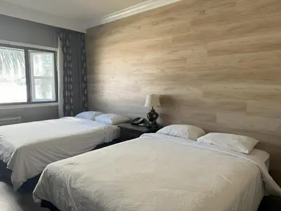 two beds in a room with wooden walls at Garden Suite Hotel and Resort in Los Angeles
