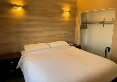 a bedroom with a white bed with a wooden wall at Garden Suite Hotel and Resort in Los Angeles