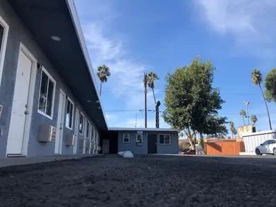 a blue and white building with palm trees in the background at New Casa Motel Los Angeles in Los Angeles