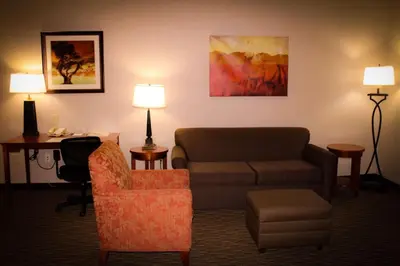 a hotel room with a couch and a chair and a desk at Best Western Plus Arrowhead Hotel in Colton