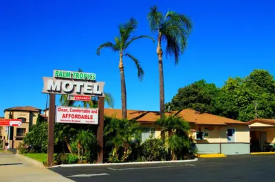 a motel sign in front of a motel with palm trees at Palm Tropics Motel in Glendora