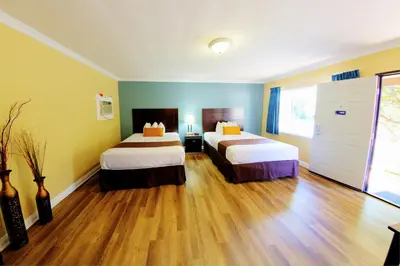 a hotel room with two beds and wooden floors at Palm Tropics Motel in Glendora