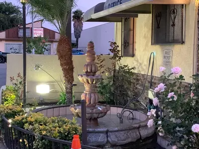 a fountain in front of a building with flowers at Apache Inn in Lynwood