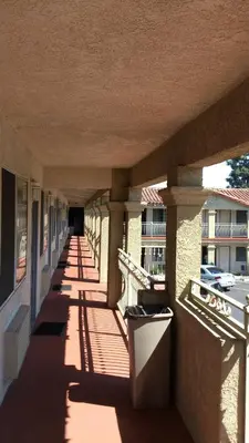 an empty corridor of a building with shadows on the ground at Santa Ana Travel Inn in Santa Ana