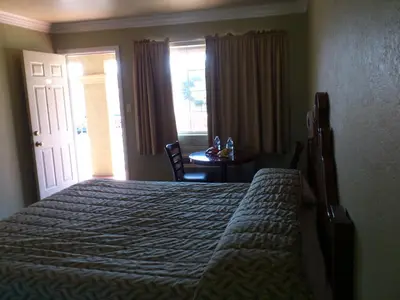 a bedroom with a bed and a table and a window at Santa Ana Travel Inn in Santa Ana