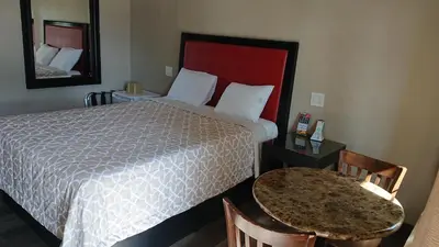 a hotel room with a bed and a table and a mirror at Santa Ana Travel Inn in Santa Ana