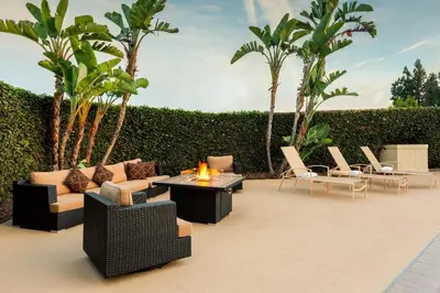 a patio with couches and tables and palm trees at Holiday Inn La Mirada Buena Park by IHG in La Mirada
