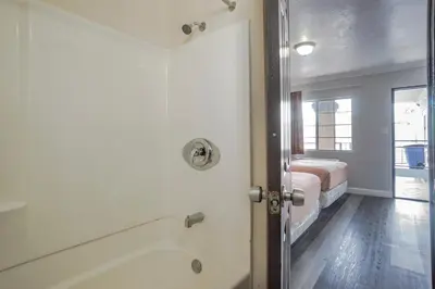 a bathroom with a tub and a bed in a room at Value Inn Hollywood in Los Angeles