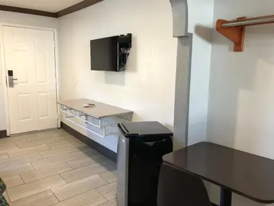 a small kitchen with a refrigerator and a tv on the wall at Starlight Inn, Valley Blvd - Downtown LA in Los Angeles