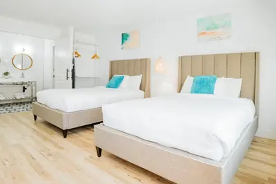 two white beds in a room with a fireplace at The Belmont Shore Inn in Long Beach