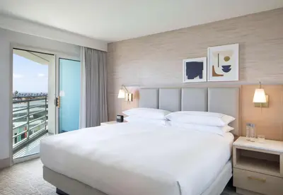 a bedroom with a large white bed and a balcony at Hilton Santa Monica in Los Angeles
