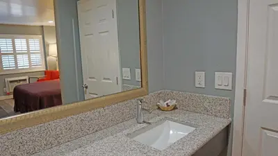 a bathroom with a sink and a mirror and a bed at Del Mar Motel in Rosemead