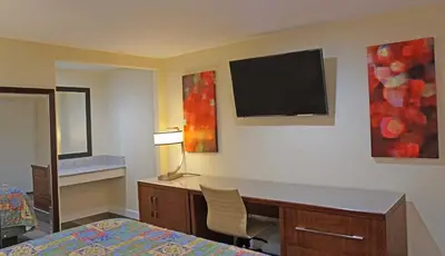 a bedroom with a desk and a tv on the wall at Del Mar Motel in Rosemead