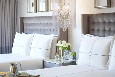 a bedroom with two white beds and a chandelier at Huntley Santa Monica Beach in Los Angeles