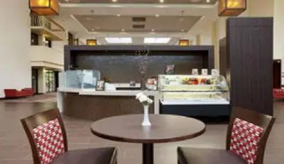 a restaurant with a table and chairs and a counter at Ontario Airport Hotel & Conference Center in Ontario