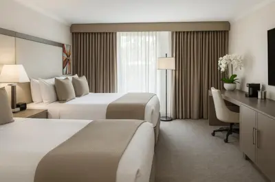 a hotel room with two beds and a desk at Ontario Airport Hotel & Conference Center in Ontario