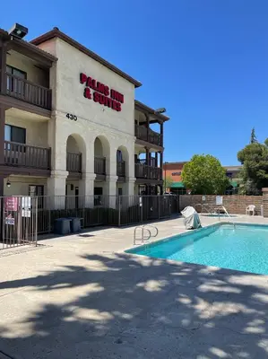 a building with a swimming pool in front of a building at Palms Inn & Suites in Palmdale