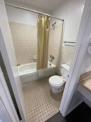 a bathroom with a toilet and a tub and a sink at Palms Inn & Suites in Palmdale