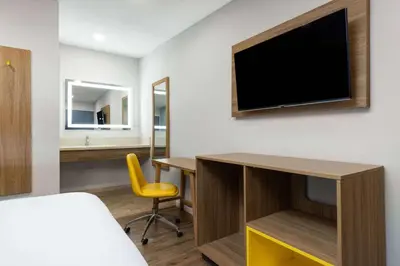 a hotel room with a desk and a tv on a wall at Days-Inn by Wyndham Bakersfield in Bakersfield