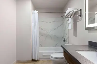 a white bathroom with a toilet and a shower at Days-Inn by Wyndham Bakersfield in Bakersfield