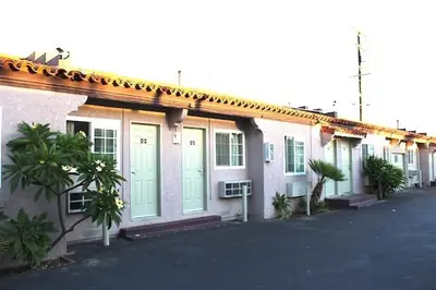 a building with green doors and trees in front of it at Beacon Motel in Long Beach