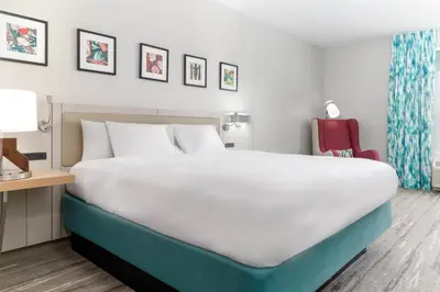 a bedroom with a large bed and a red chair at Hilton Garden Inn Ontario Rancho Cucamonga in Rancho Cucamonga