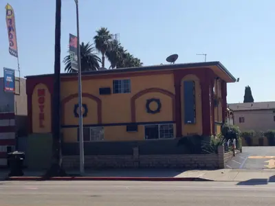 a yellow and red building with a palm tree at Economy Inn Hollywood in Los Angeles