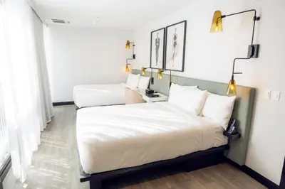 two beds in a room with white walls at The Godfrey Hotel Hollywood in Los Angeles