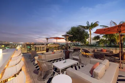 a rooftop patio with couches and tables and umbrellas at The Godfrey Hotel Hollywood in Los Angeles
