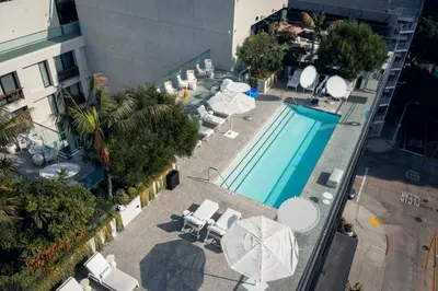 an overhead view of a swimming pool with chairs and umbrellas at The Godfrey Hotel Hollywood in Los Angeles
