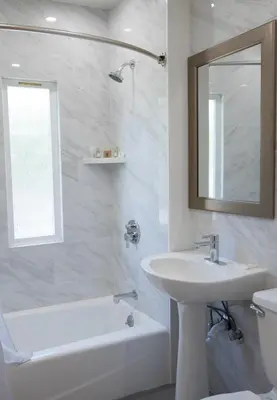 a white bathroom with a sink and a tub and a mirror at Wilshire Crest Hotel in Los Angeles
