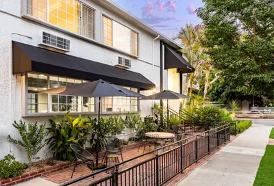 a patio with tables and umbrellas in front of a building at Wilshire Crest Hotel in Los Angeles