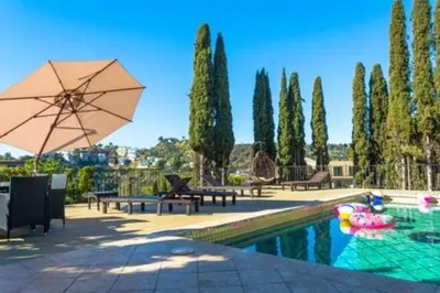 a pool with tables and umbrellas and a pool at Hollywood Hills private room in Los Angeles