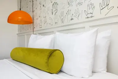 a bed with white pillows and a green pillow on it at Hotel Erwin Venice Beach in Los Angeles
