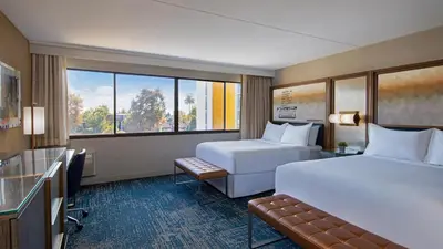 a hotel room with two beds and a window at Hotel Dena, Pasadena Los Angeles, a Tribute Portfolio Hotel in Pasadena