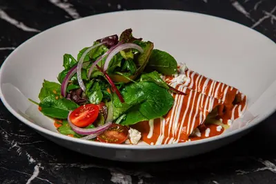 a white plate with a salad on a table at Hotel Dena, Pasadena Los Angeles, a Tribute Portfolio Hotel in Pasadena