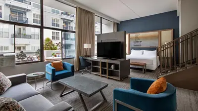 a hotel room with a bed and a living room at Hotel Dena, Pasadena Los Angeles, a Tribute Portfolio Hotel in Pasadena