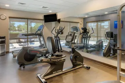 a gym with treadmills and ellipticals in front of a mirror at Comfort Suites Ontario Airport Convention Center in Ontario