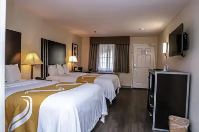 a hotel room with three beds and a flat screen tv at Quality Inn & Suites Camarillo-Oxnard in Camarillo