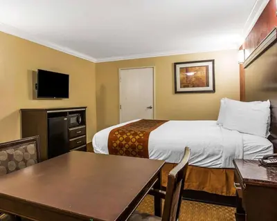 a hotel room with a bed and a table at Rodeway Inn & Suites Corona in Corona