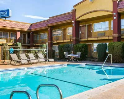 a swimming pool in front of a hotel with chairs at Rodeway Inn & Suites Corona in Corona
