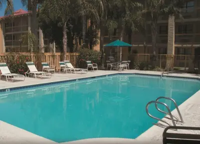 a large blue swimming pool with chairs and a table at La Quinta Inn by Wyndham Bakersfield South in Bakersfield