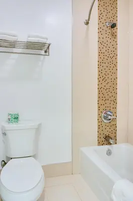 a white bathroom with a toilet and a bath tub at Eden Roc Inn & Suites near the Maingate in Anaheim