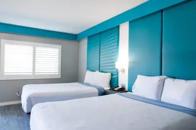 two beds in a hotel room with blue walls at Tilbury Inn in Glendale