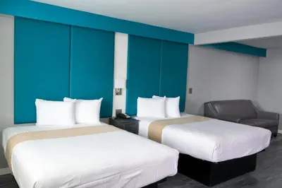 two beds in a room with blue walls and a chair at Tilbury Inn in Glendale