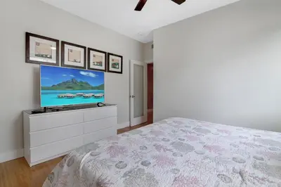 a bedroom with a bed and a tv on a wall at The Swaying Palm Haaven in Seal Beach