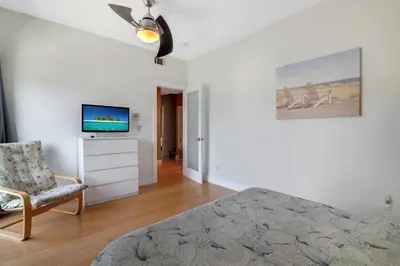 a bedroom with a bed and a tv and a chair at The Swaying Palm Haaven in Seal Beach