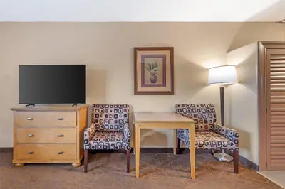 a hotel room with a desk and a tv and chairs at Best Western Plus Pavilions in Anaheim